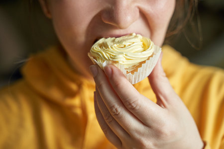 Young caucasian female enjoying delicious cupcake with creamy frosting.の写真素材