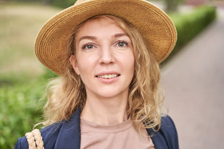 Caucasian female adult with straw hat smiling outdoors on a sunny day.の写真素材