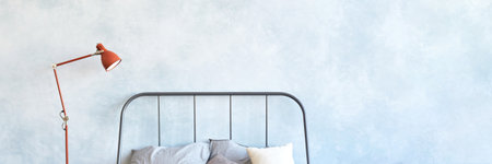 Minimalist bedroom with metal bed frame, gray bedding, red floor lamp, light blue wall, cozy decor.