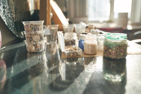 Sunlit crafting space with various jars and containers on a wooden table near a window.