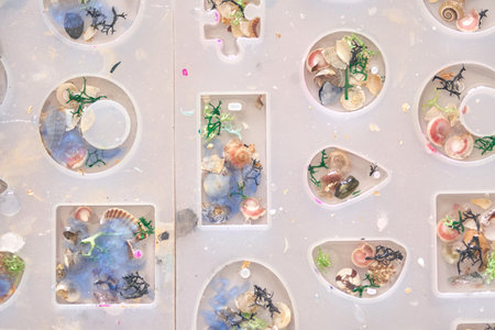 Creative resin art with colorful shells and decorative elements in mold shapes.