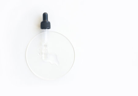 Transparent serum dropper on white surface with clear liquid for skincare and beauty treatments.の写真素材