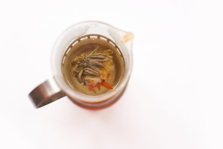 Blooming flower tea in glass teapot on white background with herbal infusion.の写真素材