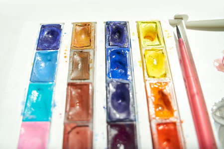 Vibrant watercolor palette with brush on white background for artistic painting and creative projects.の写真素材