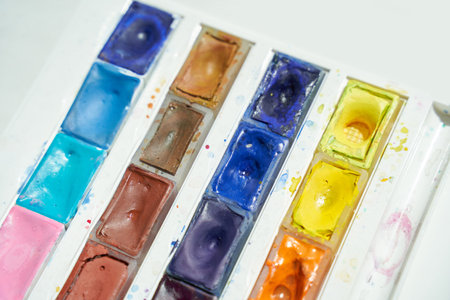 Bright watercolor palette with vibrant colors and used paint trays in sunshine.の写真素材