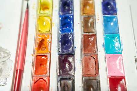 Vibrant watercolor paint set with brushes in close-up view for artistic creativity and color mixing.の写真素材