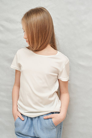 Young caucasian girl in white t-shirt and jeans posing against gray background.の写真素材