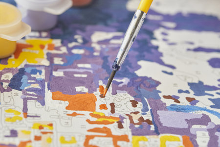 Close up of paintbrush on colorful paint by numbers canvas with bright colors and detailed patterns.の写真素材