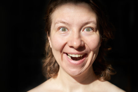 Joyful caucasian female adult with light eyes expressing happiness in close-up image.の写真素材