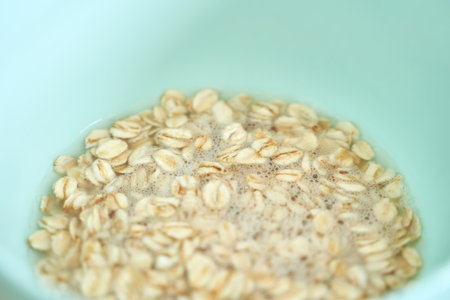 Rolled oats in water inside light blue bowl for healthy breakfast preparation.の写真素材
