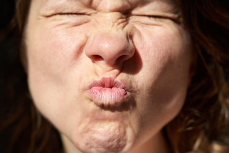 Caucasian female adult making a funny expression with eyes closed and lips puckered.の写真素材