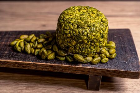 Goat cheese balls wrapped with pistachio. Cheese on black background. Traditional dinner. High...