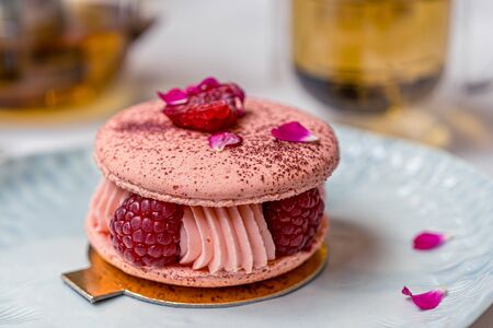 Beautiful Pink Raspberry Macaron cookies on blue plate. Healthy food. Blue table background. Top view.の写真素材