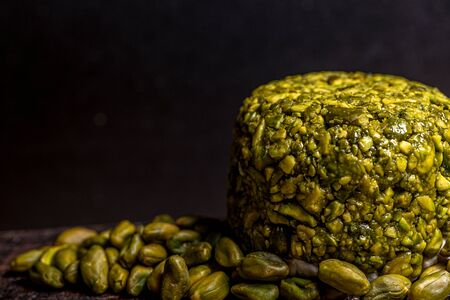 Goat cheese balls wrapped with pistachio. Cheese on black background. Traditional dinner. High...