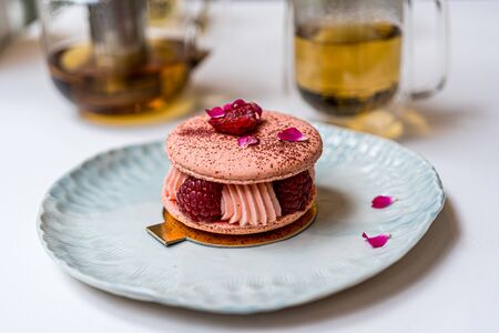 Pink Raspberry Macaron cookies on blue plate. Tea time. Blue table background. Top view.