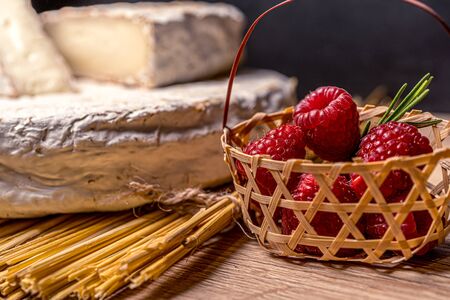 Cheese Camambert with raspberry basket. Rustic set on black backdrop. Healthy fresh nutrition. Healthy food background.の写真素材