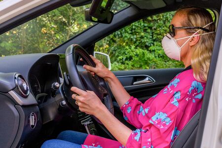 woman drives a car in protective mask during the world pandemic of the coronavirusの写真素材