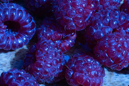 Abstract raspberry close up macro. Blue background. Fresh fruit. High quality photoの写真素材