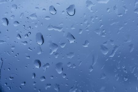 Raindrops on the window. Beautiful closeup. Blue background. Water splash. Natural background. High quality photoの写真素材