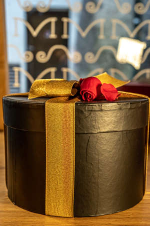 Golden ribbon with red rose on the gift box. Holiday party decoration. Season greeting background. Winter holiday. Festive event.の写真素材