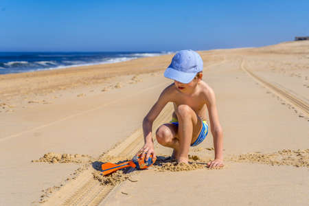 Boy playing on the beach. Activity nature leisure. Happy cheerful boy. Summer vacation concept.の写真素材