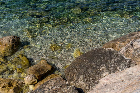 Stones in the water. Abstract green closeup on transparent background. Beach vacation. Water splash. Foam water. Liquid texture background. High quality photoの写真素材