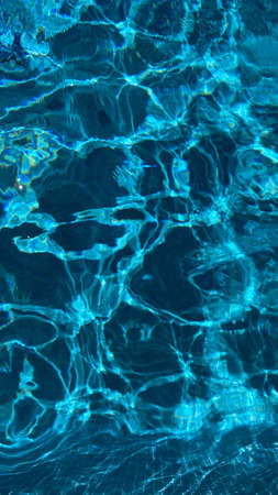 Swimming pool water texture in abstract style on blue background. Vacation, holiday. Ripple water. Swimming pool water sun reflection background. Summer vacation.の写真素材