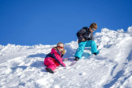 Two joyful kids playing on the snowing mountain on a winter day. Brother and sisterの写真素材