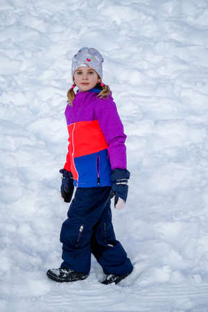Outdoor winter portrait of little cute girl wearing ski clothes. Girl walking in the snow. Stylish clothes for kids.の写真素材