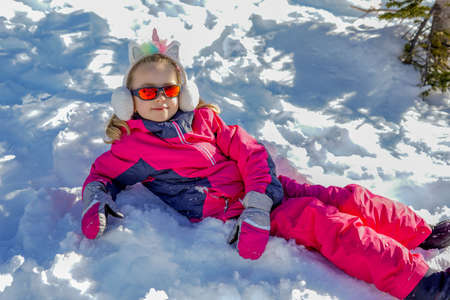 Young girl with sunglasses sitting on the snow place. Winter timeの写真素材