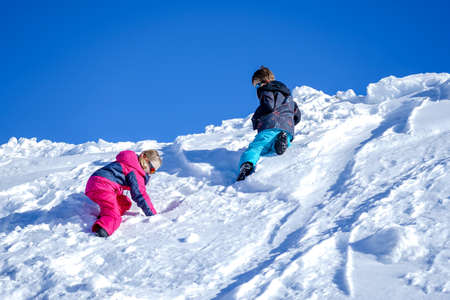 Two joyful kids playing on the snowing mountain on a winter day. Brother and sisterの写真素材