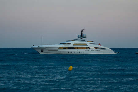 Modern luxury yacht on the sea and flying passenger plane later evening