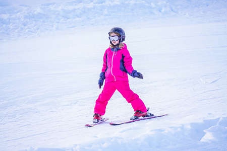 Little girl is learning to ski in ski resort. Winter season.の写真素材