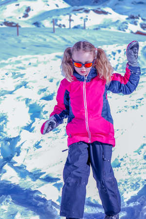 Soft focus background. Young girl descends from the snow mountain in winter clothes. Snow background.の写真素材