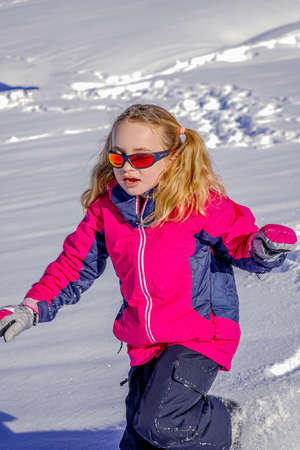 Soft focus background. Young Girl With Sunglasses Playing In The Snow. Winter sunny day on the french alpsの写真素材