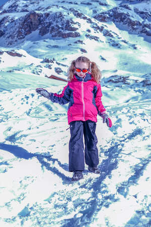 Soft focus background. Young girl descends from the snow mountain in winter clothes. Snow...