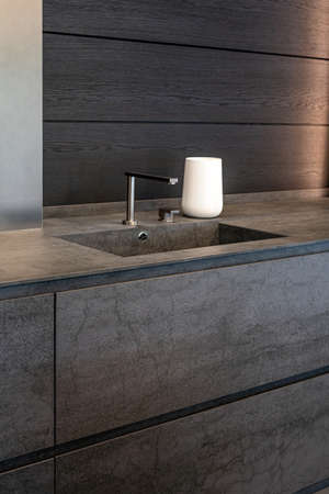 Dark beige marble wash basin with glossy metal mixer. White decorative vase. High quality photoの写真素材