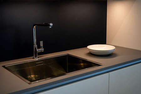 Black kitchen sink and Tap water in the kitchen. The interior of the kitchen room of the apartment. Domestic Appliances. White Platesの写真素材