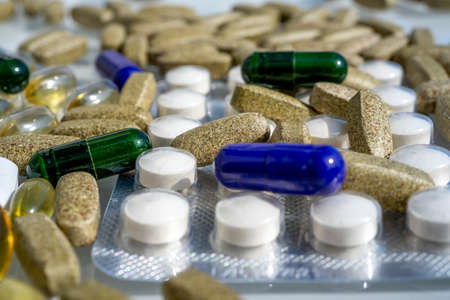 Close-up of different pills and capsules are on the table from virus. Selective focus. Assorted pharmaceutical medicine pills, tablets and capsules.の写真素材