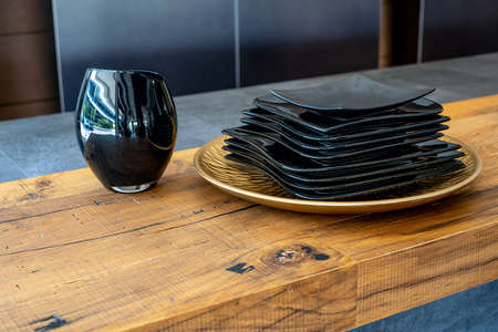 The black plates and vase on a kitchen wooden board. Modern kitchen accessories, interior design. High quality photoの写真素材