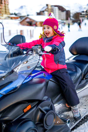Funny Girl sitting on a quad bike in the winter in the French Alps. All terrain vehicle in motion at winter.の写真素材