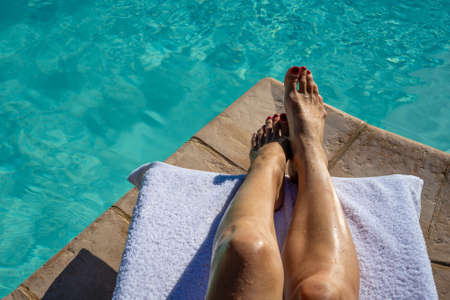 Close up woman feet relaxing near swimming pool background in summer conceptの写真素材