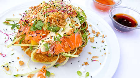 Sushi-food hybrids trend. New Design Delicious White Rice Hamburger ingredients salmon, avocado, mayonnaise, fresh vegetables and fruits, fried onion. Soft focus backgroundの写真素材