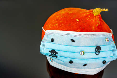 Pumpkin for Halloween with Surgical mask with skulls and rhinestones. Halloween pumpkin head. QUARANTINE, PANDEMICの写真素材