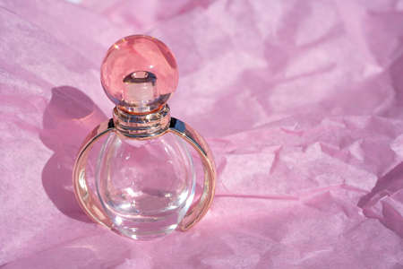 Bottle of Perfume - Fragrance bottle in pink and gold on the rose color paper background. Close-up