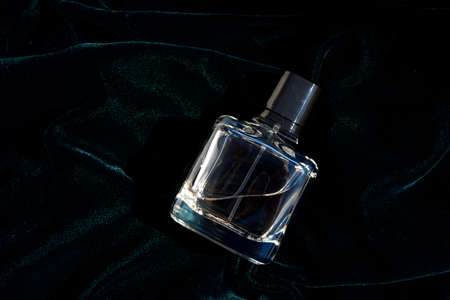 Bottle of Perfume - Fragrance bottle in dark green and blue color cloth background. Close upの写真素材