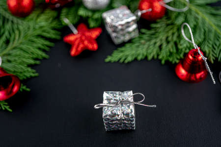 Christmas composition with silver gift on black color background. Blurred focus, fir tree and gifts, red toys. Winter holiday theme. Space for text. Happy new yearの写真素材