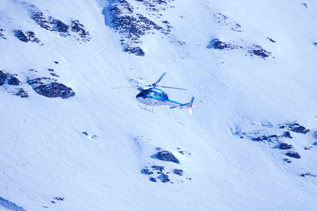 Helicopter landing on snow mountain in L'Alpes D'Huez, France. The helicopter service in offers scenic flights, glacier landing and emergency rescue. Blue mountainのeditorial素材
