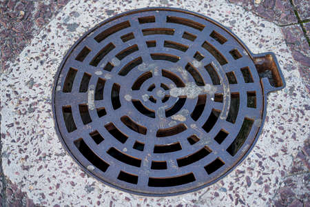 Abstract circle iron metal drain lid or round manhole drain cover texture on concrete pavement...