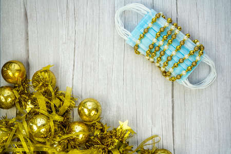 Composition with blue medical corona virus face masks and winter decoration with gold balls on...